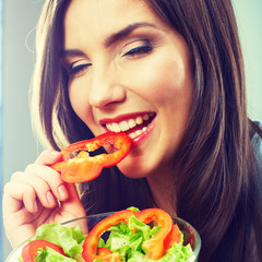 Woman eating green salad . Female model close up face studio iso