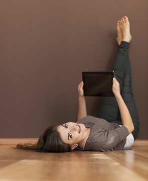 Happy woman lying on floor with digital tablet
