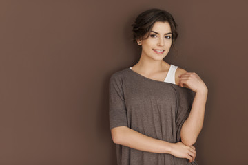Fototapeta premium Portret uśmiechnięta kobieta na brązowej ścianie