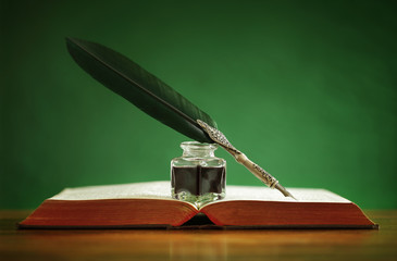 Quill pen and inkwell on old book