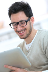 Young man with eyeglasses websurfing with tablet