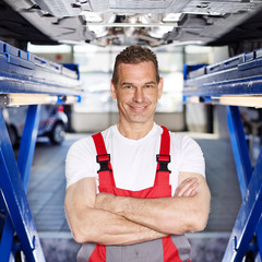 Master mechanic under a service lift in a garage