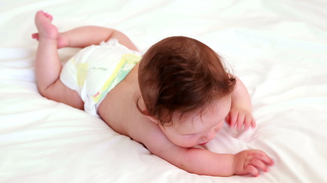 Baby in diaper lying on bed