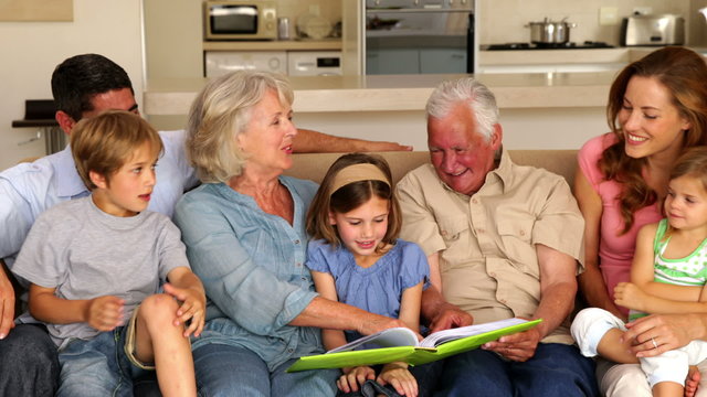 Extended family looking at photo album together on couch