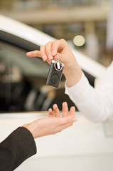 Female hand getting modern car key on a car background