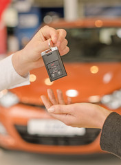 Female hand getting modern car key on a car background