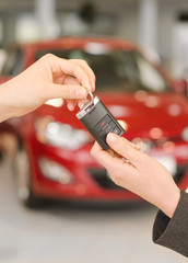 Female hand getting modern car key on a red car background