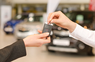 Female hand getting modern car key on several car background