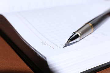 Pen on opened book on brown table