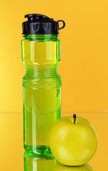 Sports bottle with apple on yellow background