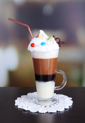 Glass of coffee on color wooden table, on dark background