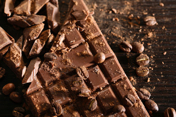 Chopped bar of chocolate on wooden background