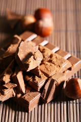 Chopped bar of chocolate on bamboo mat background