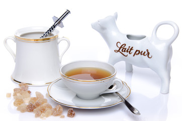 A cup of tea with sugar and milk jug