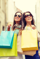 two girls in sunglasses with shopping bags in ctiy