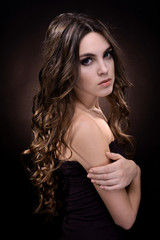 Fototapeta premium Beautiful young woman with long hair on dark brown background