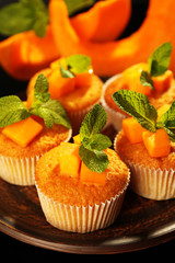 Tasty pumpkin muffins on dark background