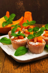 Tasty pumpkin muffins on wooden table