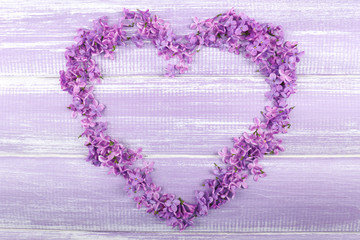 Beautiful lilac flowers in shape of heart on wooden background © Africa Studio