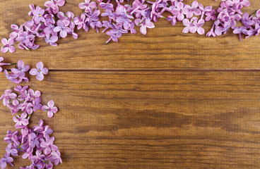 Fototapeta na wymiar Beautiful lilac flowers frame on wooden background