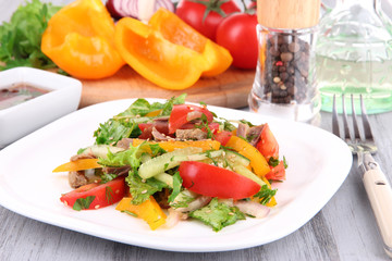 Beef salad on plate with vegetables and spices on wooden table