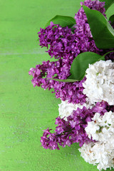 Beautiful bouquet of lilac flowers on color wooden background