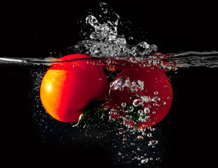 Two tomatoes falling into water