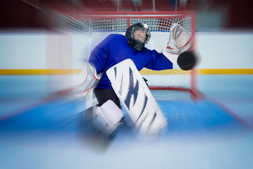Young hockey goalie catching a flying puck