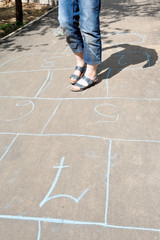 girl playing in hopscotch on urban alley