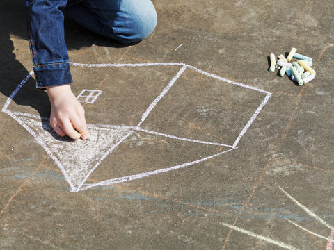 Girl Drawing House With Colored Chalk On Pavement