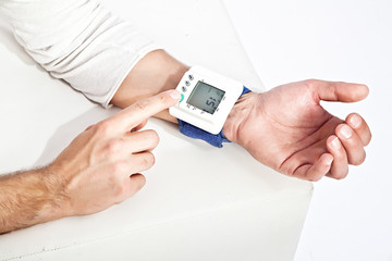Photo of young man’s hand measuring his blood pressure - obrazy, fototapety, plakaty
