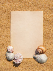 Sheet of paper and seashells on the sand