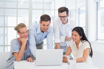 Casual business team looking at laptop together