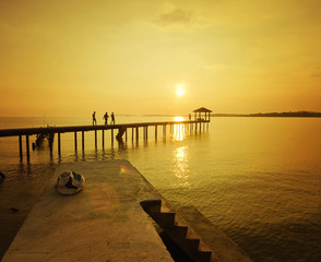 Obraz premium sylwetka człowieka idącego na molo podczas złotego zachodu słońca