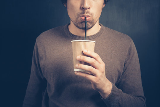 Young man drinking from paper cup with straw