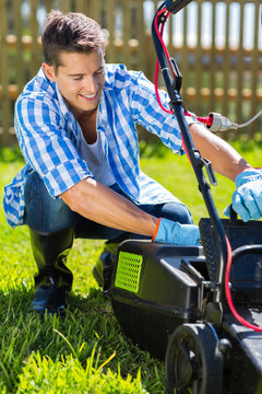 young man emptying lawnmower grass catcher