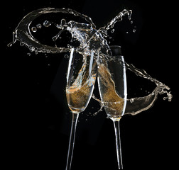 Glasses of champagne with splash, on black background