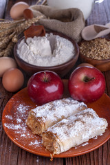 .apple pie on a wooden table with flour and grain