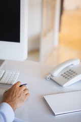 Casual businessman at desk with notepad and telephone