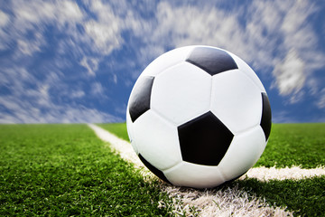 Fototapeta premium soccer ball on grass field with blue sky