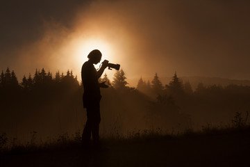 silhouette of woman photographer taking photos in forest with fo