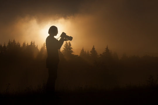 silhouette of woman photographer taking photos in forest with fo