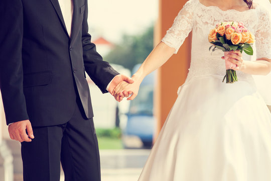 Wedding couple holding hands with flower holding