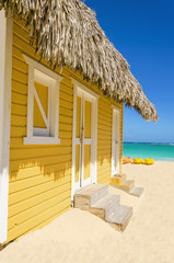 Wooden yellow beach cottage on the sandy beach with kayaks