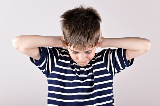 Young boy bending his head and covering ears with hands