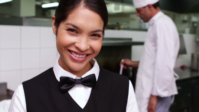 Smiling waitress being handed a dish by chef