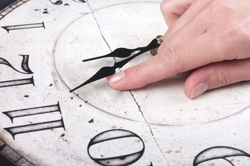 Weibliche Finger ändert die Zeit auf einer Uhr