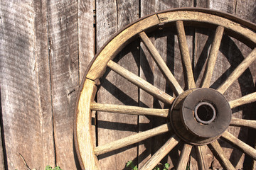 Wooden wheel leaning against barn