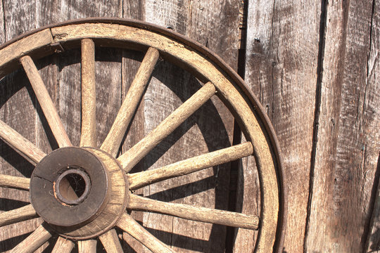 Wooden wheel leaning against barn