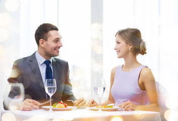 Obraz na płótnie Canvas smiling couple eating main course at restaurant